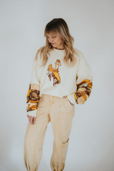 Woman looks down over her shoulder as she wears the RUBY WYLD signature collection Wyoming Cowboys sweater 