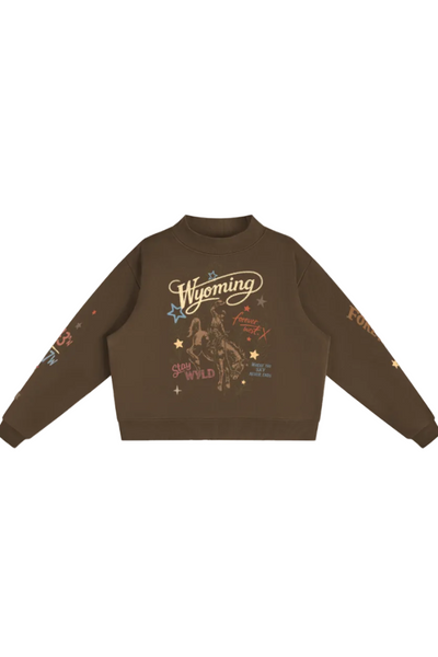 A dark brown crewneck sweatshirt featuring a western-themed graphic print on the front with 'Wyoming' in script, a cowboy on a bucking horse, and stars, shown against a plain white background.