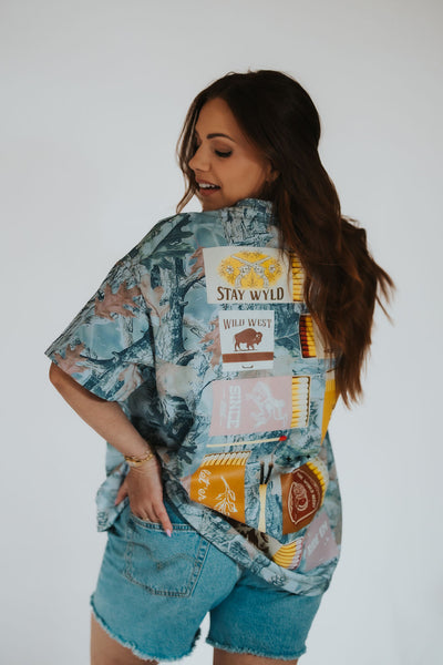 woman poses to the back in her custom RUBY WYLD oversized women's camo t-shirt with Wyoming matchbook detailing and designs