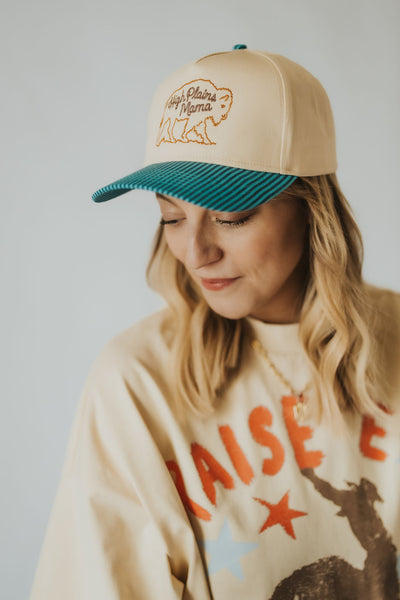 Stylish Wyoming woman smiles and looks down over her shoulder in the RUBY WYLD custom embroidered motherhood hat 