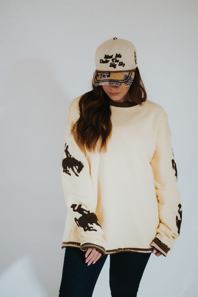 Person wearing a butter yellow-colored sweater with Wyoming bucking horse logos.