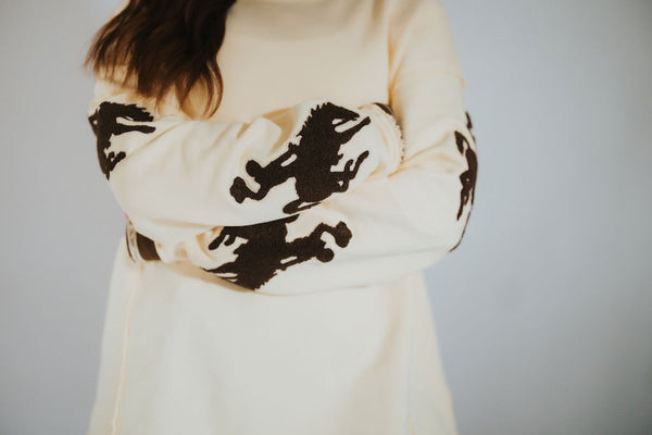Person wearing a butter yellow-colored sweater with Wyoming bucking horse logos.