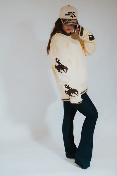 Person wearing a butter yellow-colored sweater with Wyoming bucking horse logos.