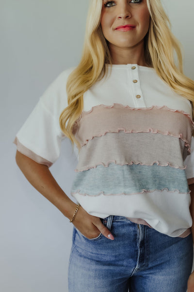 This cutie is super soft, features multi-colored wide ruffled stripes in pastel hues, a wide scoop neckline, short sleeves with pink edging + non-functional button down detail. With a perfectly loose fit, style it with your fav cargos or jeans + sneakers for an effortlessly casual yet cool vibe.