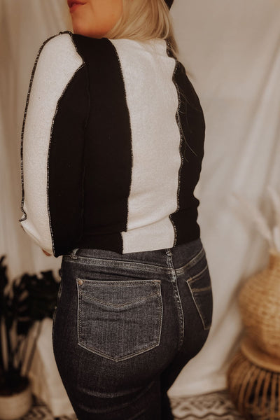 Contrasting black and white knit sweater top Mock neckline Exposed seam detail