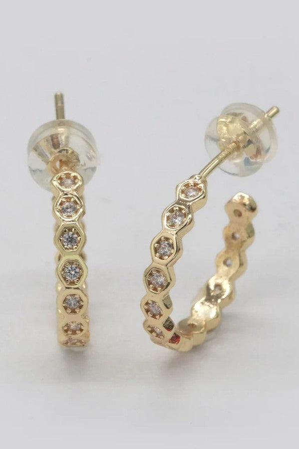 These earrings feature a sleek gold hoop design adorned with geometric-shaped cubic zirconia stones bezel-set for a modern touch of sparkle.