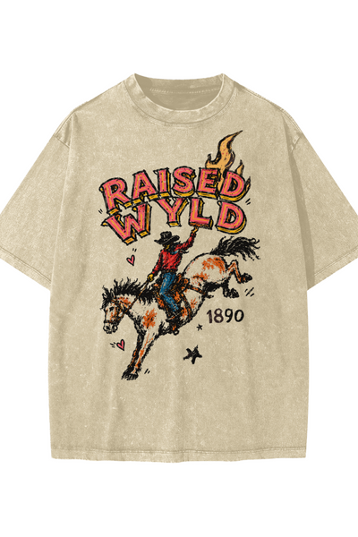 A beige mineral-wash graphic t-shirt featuring a cowboy riding a bucking horse with the text 'RAISED WYLD' and '1890' printed on the front.